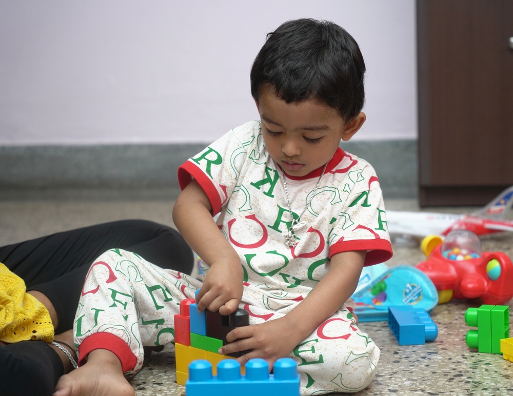 child reachng developmental milestones with building blocks